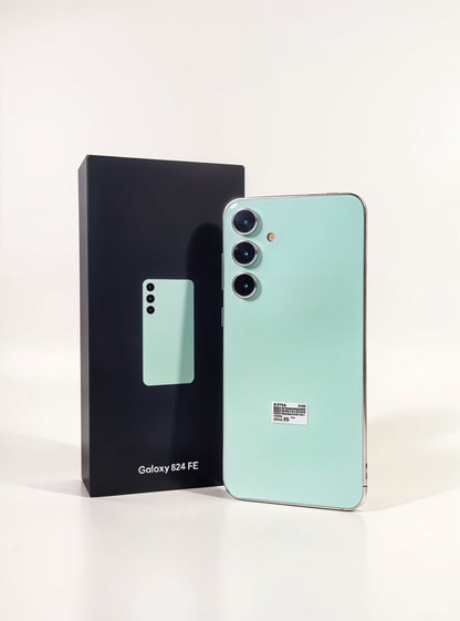 Mint green smartphone next to its packaging on a white background